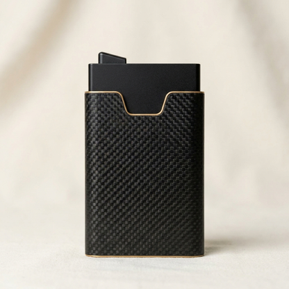 A slim black card holder or wallet with a carbon fiber textured exterior and a matte black interior, standing upright on a light beige surface.